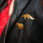 Pins tamanoir finition or et pins kiwi finition or portés sur une veste en cuir- Les Naturalistes bijoux
