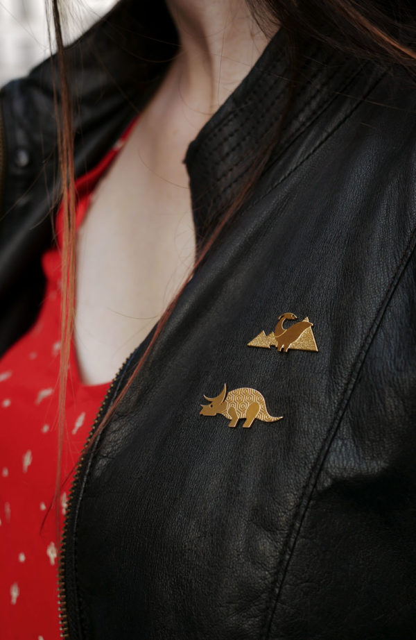 Pins dinosaure et pins tricératops finition or portés sur une veste en cuir - Les Naturalistes bijoux
