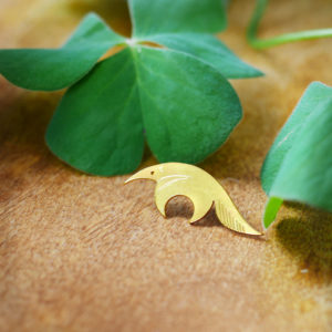 Pins tamanoir finition or avec un trèfle sur une table en bois- Les Naturalistes bijoux