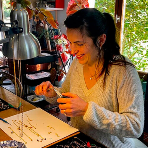 Myriam montant les bijoux à la main dans l'atelier en bord de forêt