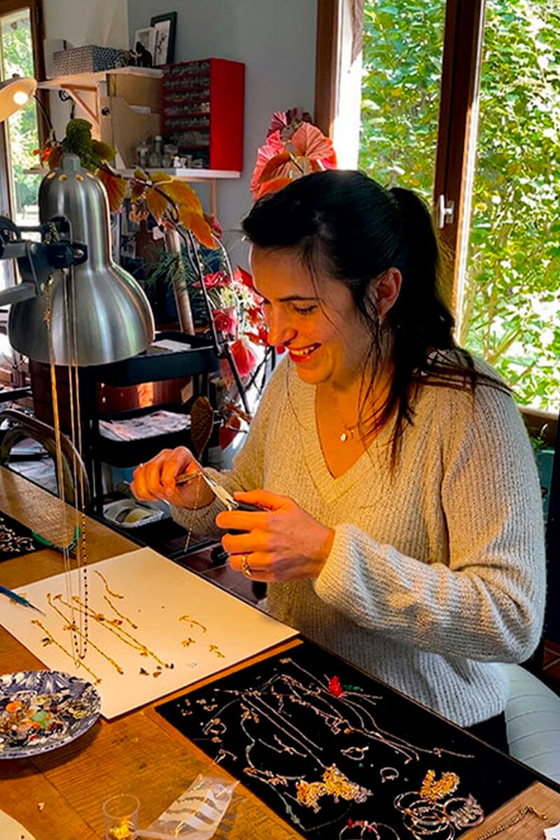 Myriam montant les bijoux à la main dans l'atelier en bord de forêt