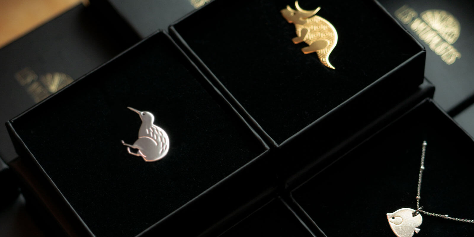 Mise en scène de colliers et pins en laiton doré dans leur packaging soigné - Les Naturalistes bijoux